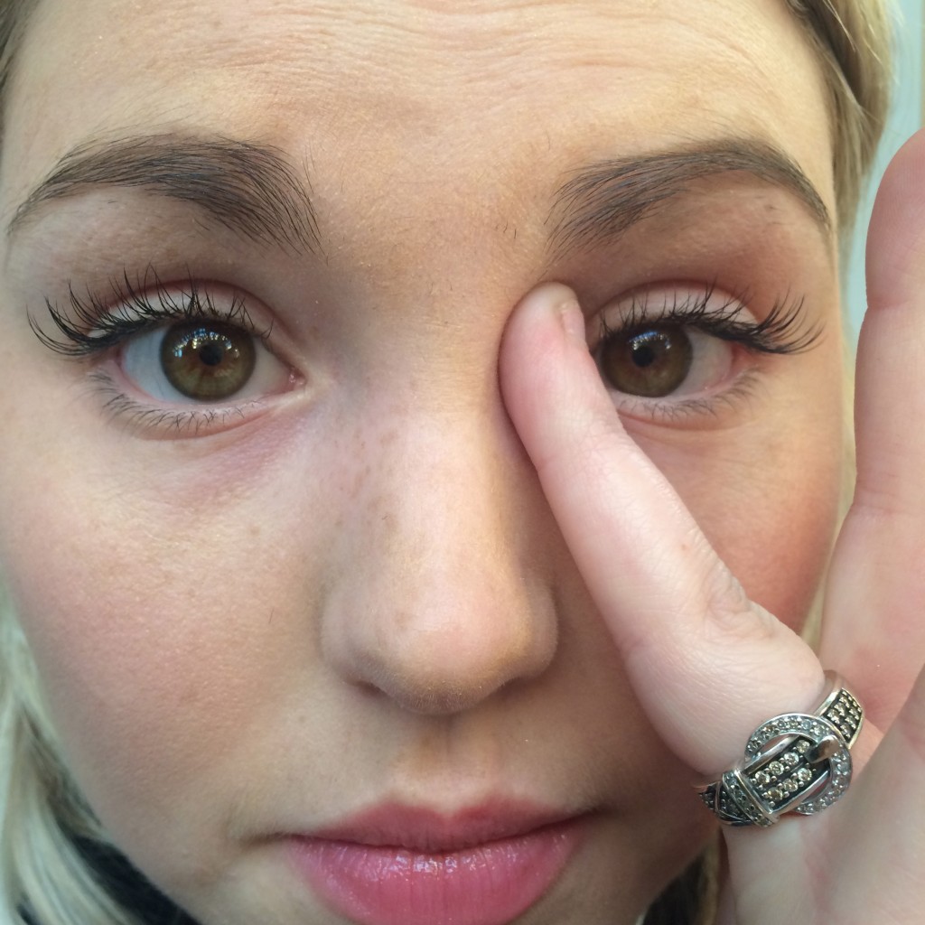 a girl pressing the under-eye concealer into the inner corners of her eyes where the skin is darkest