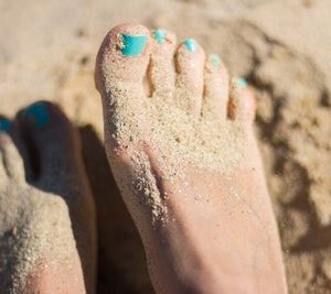 barefoot in the sand with blue nail polish