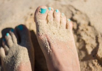 barefoot in the sand with blue nail polish