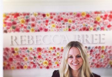 Rebecca bree in her Boutique, in front of the Rebecca Bree sign